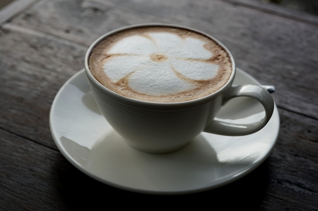 Чашка горячего кофе латте арт на деревянном столе