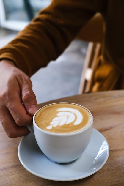 朝食のためのテーブルの上の熱いラテコーヒーのカップ