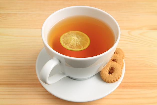 Cup of hot lime tea with cookies isolated on wooden table