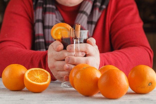 Cup of hot mulled wine and oranges on wooden tab