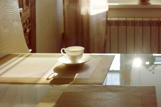 Cup of hot steaming coffee on a sunny morning on the kitchen table