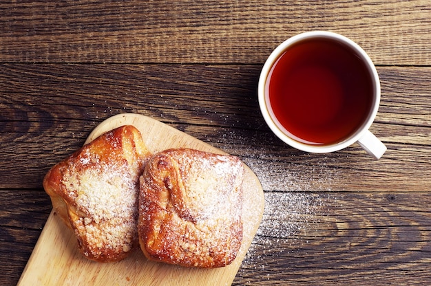 テーブルの上の熱いお茶と甘いパンのカップ