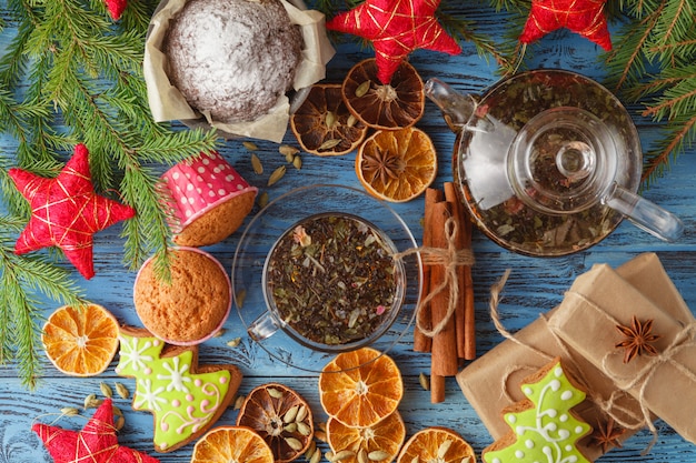 cup of hot tea and a teapot. cinnamon, anise, cookies and spruce branches on a wooden table.