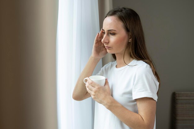 Photo a cup of hot tea will calm the soul an unhappy young woman drinking tea and looking out the window