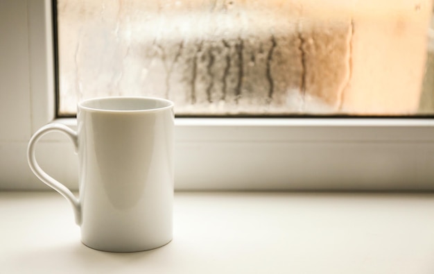 Photo cup of hot tea on window sill