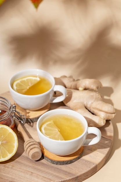 Чашка горячего чая с имбирным медом и лимоном на бежевом фоне вертикальное фото