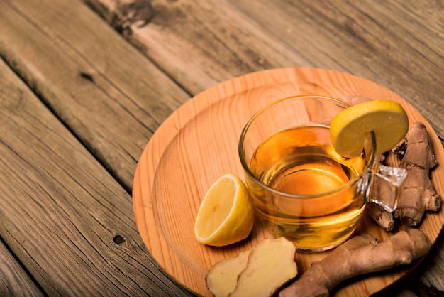 Foto tazza di tè caldo con radice di zenzero, limone e curcuma aggiungendo miele crudo naturale alla tazza di vitamina del tè caldo