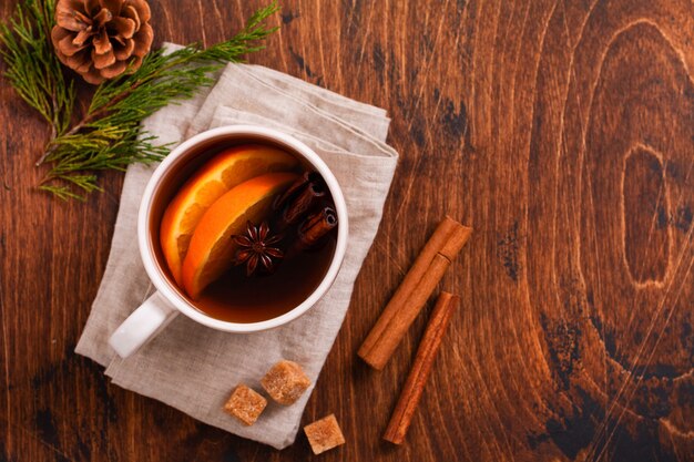 Cup of hot tea with orange and spices on a rustic brown background. Close-up