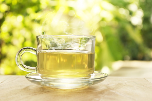 Tazza di tè caldo con fumo su uno sfondo sfocato della natura.