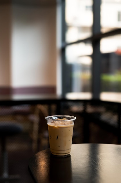 A cup of iced coffee sits on a table in a cafe.