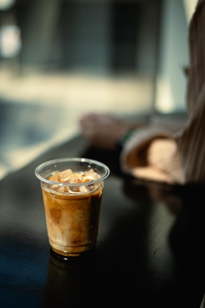 A cup of iced coffee sits on a table in front of a person.