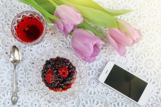 Cup of karkadeh red tea with berries cake and tulips