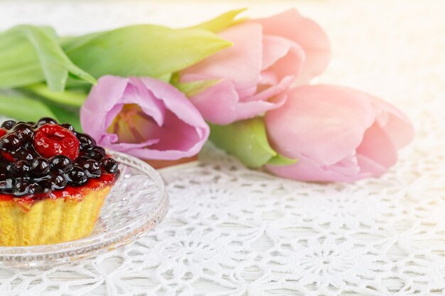 Foto tazza di tè rosso karkadeh con torta di frutti di bosco e tulipani