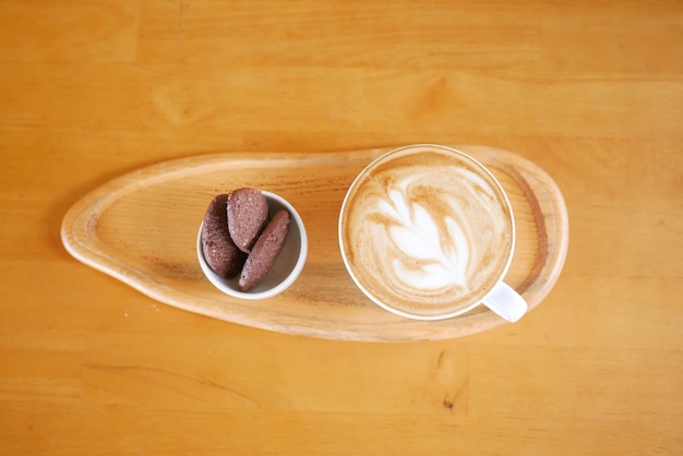 カフェで花の形のデザインが施された遅いコーヒーのカップ