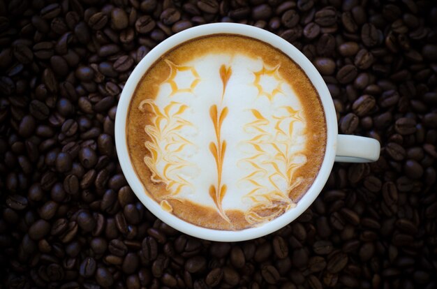 コーヒー豆の背景にラテアートのカップ