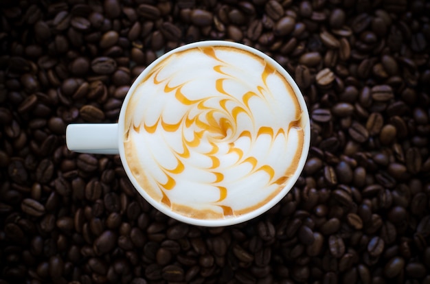 a cup of latte art on coffee bean background