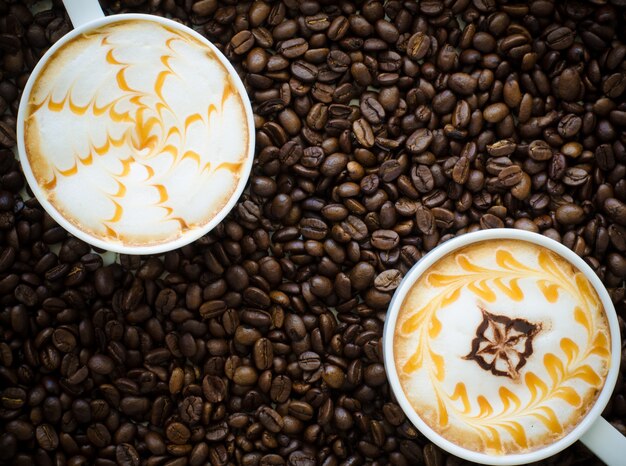 Чашка латте искусства на фоне кофейных зерен