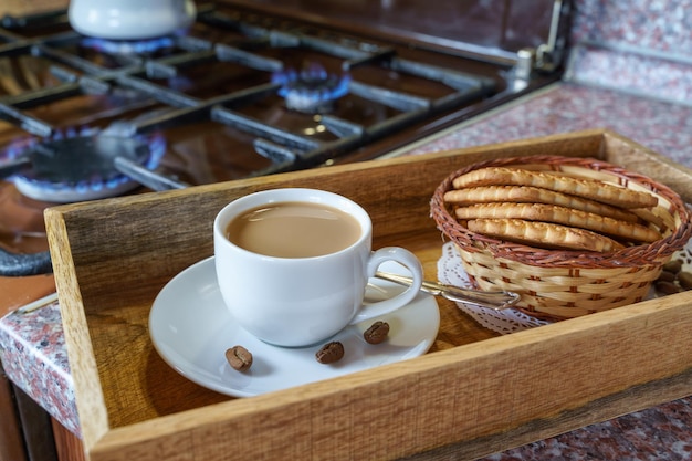 Чашка кофе латте-арт и печенье перед газовой плитой в загородном доме