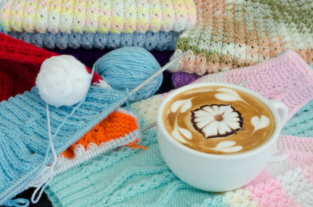 Una tazza di latte art su uno sfondo di maglia a maglia