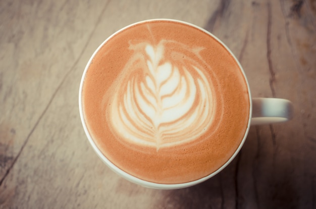 Una tazza di arte del latte su fondo di legno, filtro d'annata