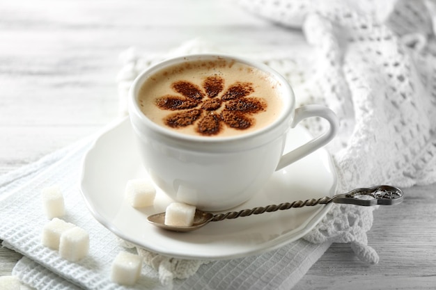 Cup of latte coffee art on wooden table on light background