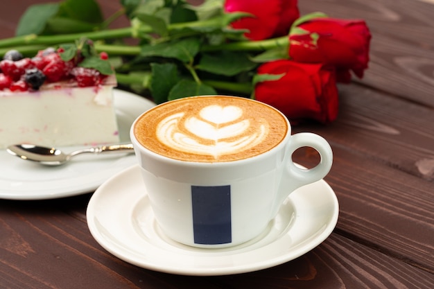 Чашка кофе латте с кусочком ягодного чизкейка крупным планом