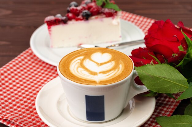 Cup of latte coffee with piece of berry cheesecake