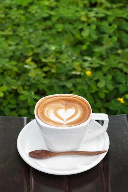 Cup of latte coffee on wood background