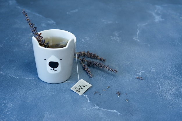 Una tazza di tè alla lavanda per sogni d'oro. fiori di lavanda su sfondo blu pietra