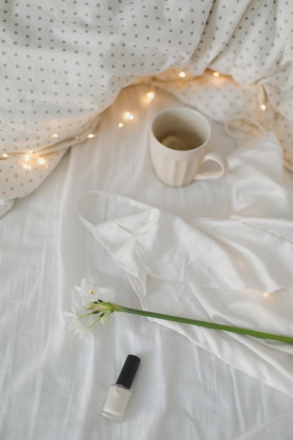 Cup of lemon tea daffodil flower and accessorries on bed\
breakfast in bed morning spring