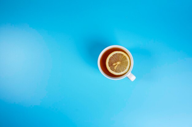 Foto una tazza di tè al limone sullo sfondo blu