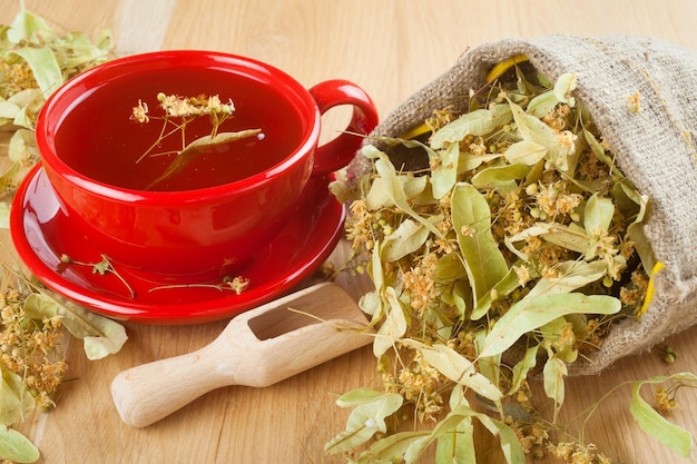 Photo cup of linden tea and flowers in canvas bag on wooden table