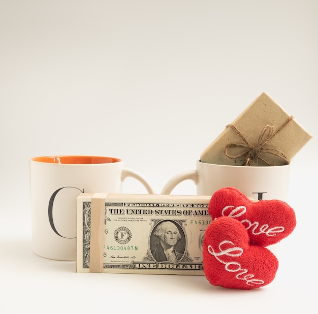 Photo cup of love,two coffee cups with red heart icon,dollar bank note,gift box  on white background,valentines concept