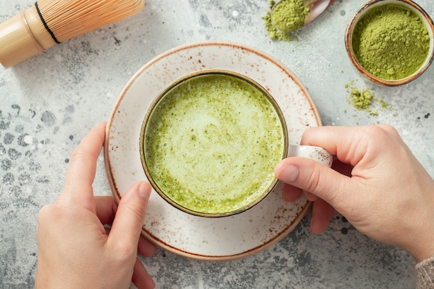 Cup of Matcha Green Tea in woman hands.