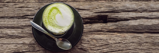 Cup of matcha latte against the old wooden table banner long format