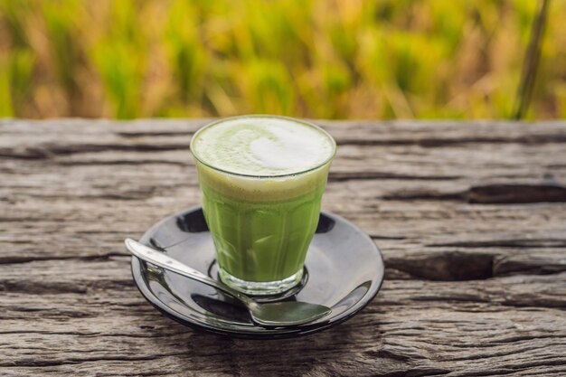 Cup of matcha latte against the old wooden table