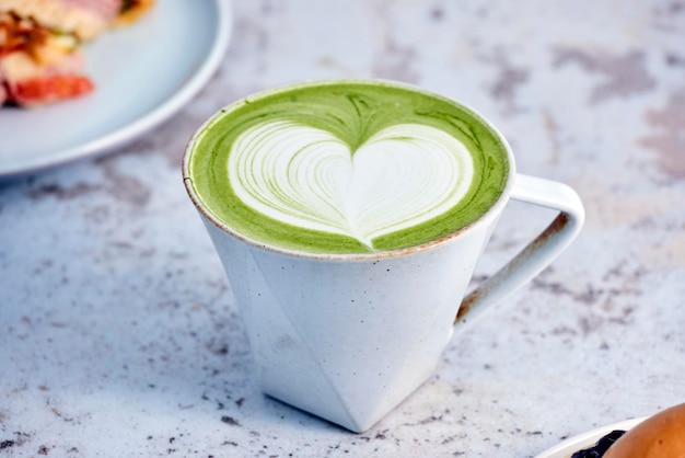 A cup of matcha latte with a heart shape on the rim