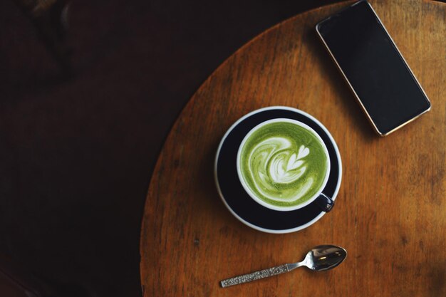 A cup of matcha latte on wooden table