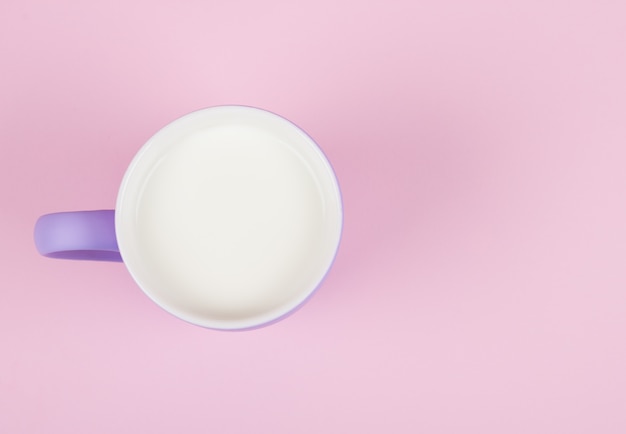 Tazza di latte contro uno sfondo rosa pastello