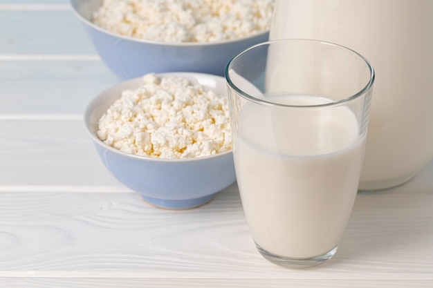 Cup of milk and cottage cheese in bowl on table