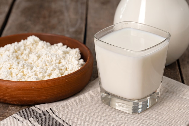 Cup of milk and cottage cheese in bowl on table