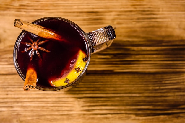 Cup of mulled wine with cinnamon on rustic wooden table. Top view