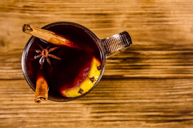 Cup of mulled wine with cinnamon on rustic wooden table. Top view