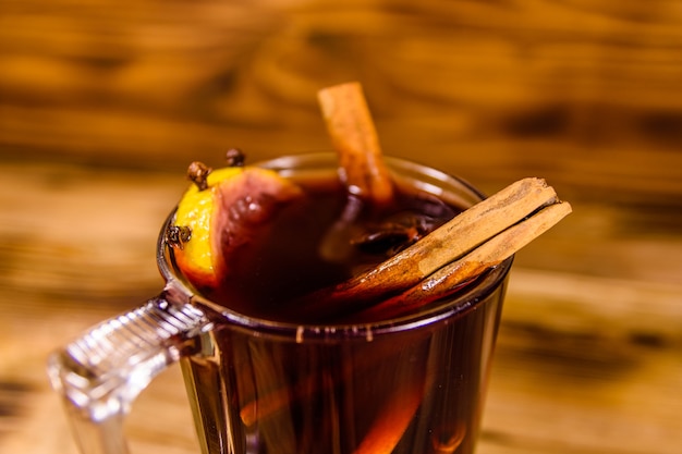 Cup of mulled wine with cinnamon on rustic wooden table