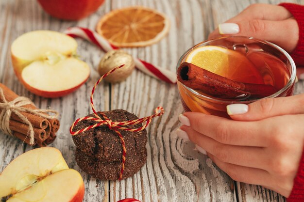 Cup of mulled wine in woman's hands on wooden table