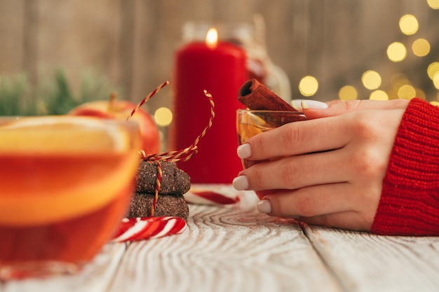 Cup of mulled wine in womans hands on wooden table