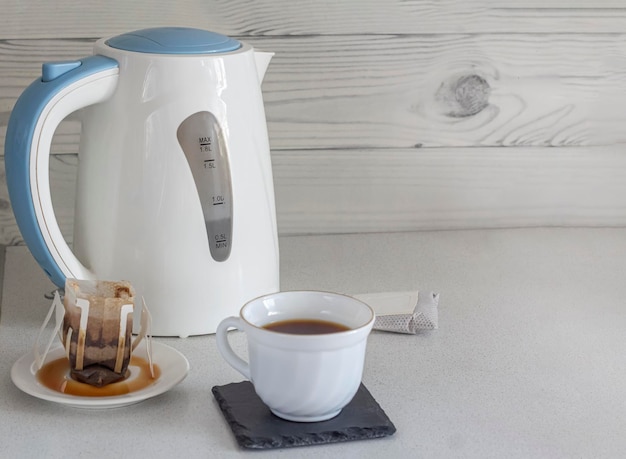 A cup of natural coffee from drip bags for brewing on the background of a teapot closeup with a copy of the space