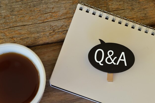 A cup of nescafe notebook and wooden tag written with Q and A