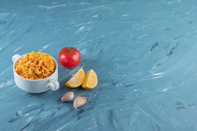 A cup of noodle next to vegetables, on the marble background. 