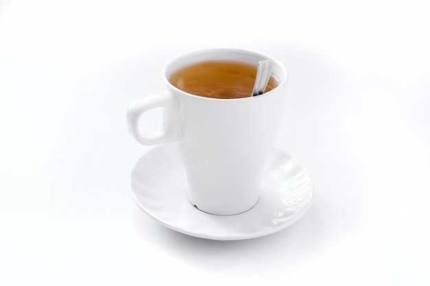 Фото Чашка черного чая с блюдцем и ложкой на белом столе